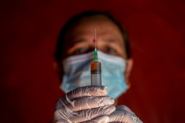 A woman veterinary worker prepares vaccines in Nepal.