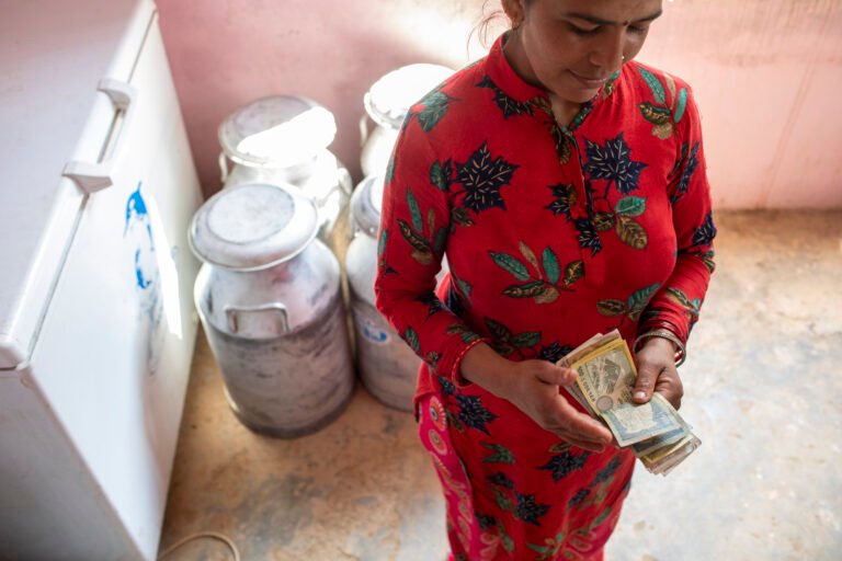 A woman in Nepal counts money after selling milk to a local milk collection center.