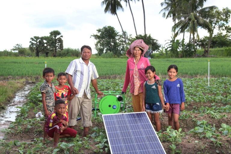 Two adults and five children posed next to solar-powered irrigation pump