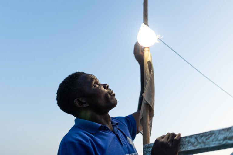A Liberian fisherman adjusting a light on his boat