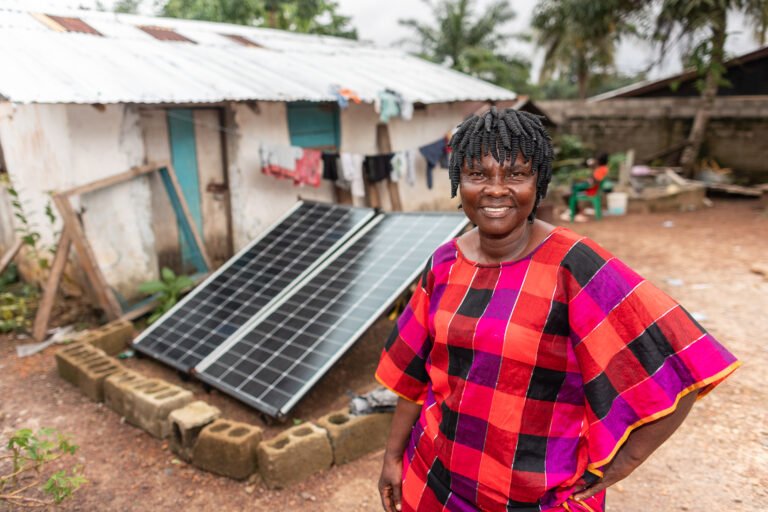 A Liberian female small business owner standing in front of solar panels