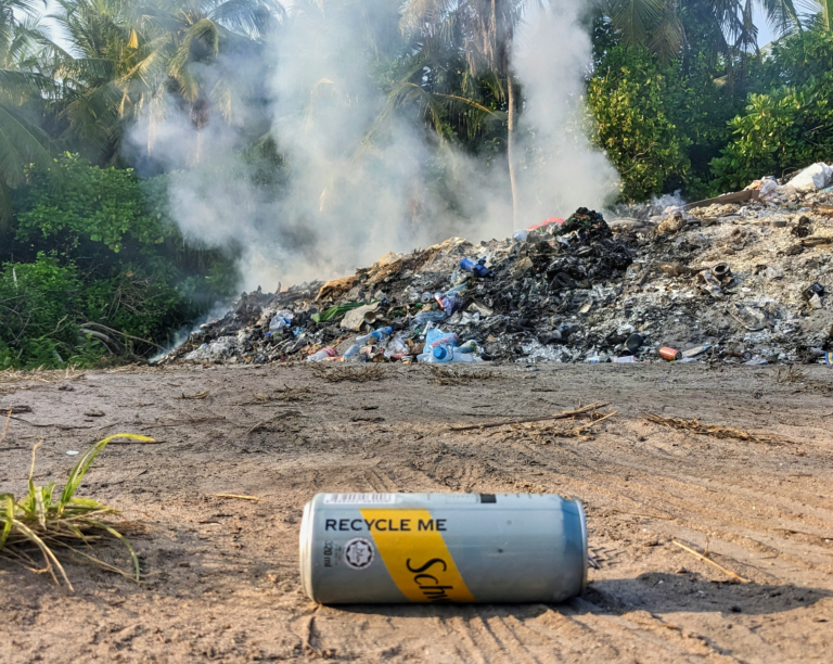 A solitary canned drink implores 'Recycle Me' against the harsh backdrop of a smoldering waste site, Dhigurah, Maldives - 23rd February, 2023.