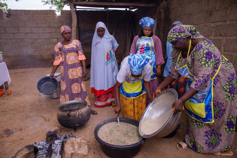Group of women around large pot of soup