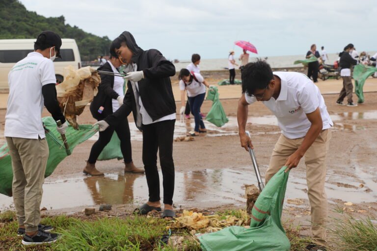A dozen young people picking up trash on a beach.