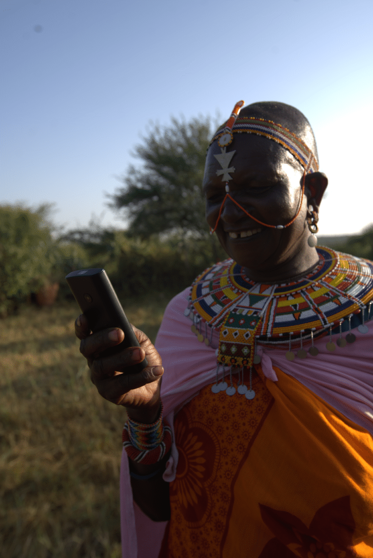 A local farmer smiles while looking at phone.