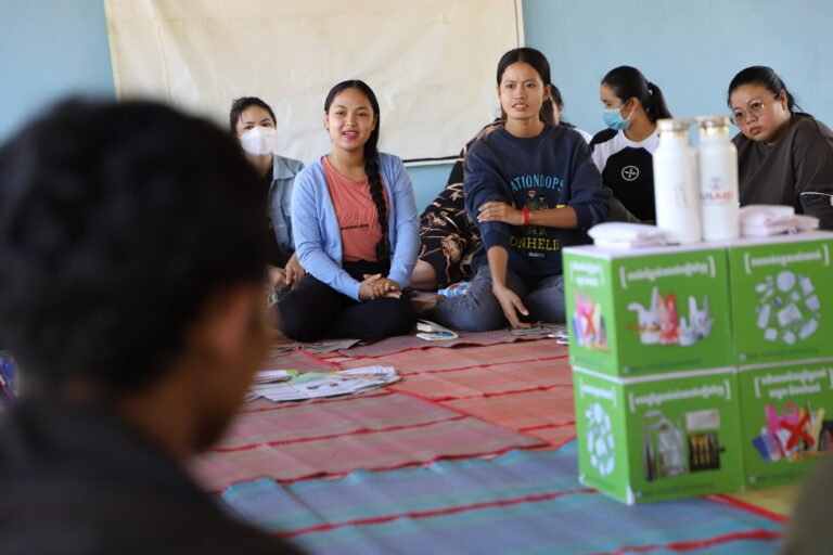 A group of women sit on the floor in a classroom.