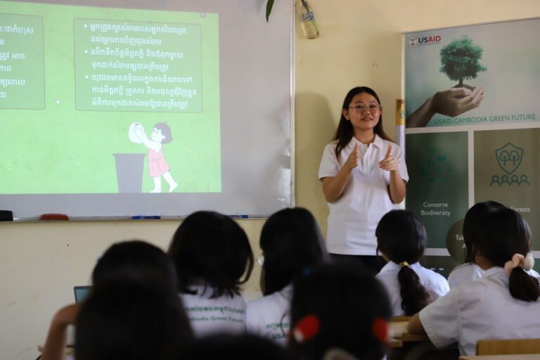 A young woman stands in front of a class giving a presentation.