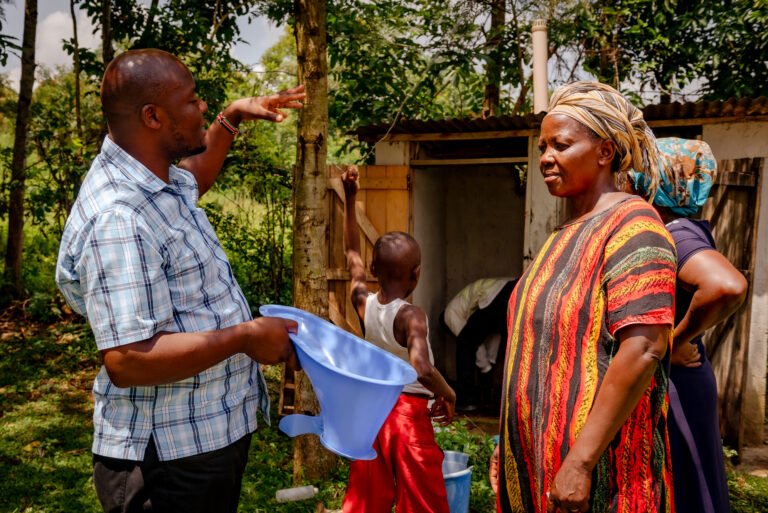 Man speaking to a  woman with a latrine and several other people in the background.