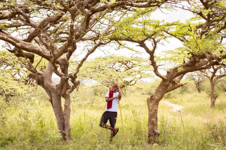 A man poses standing on one leg in between two trees.