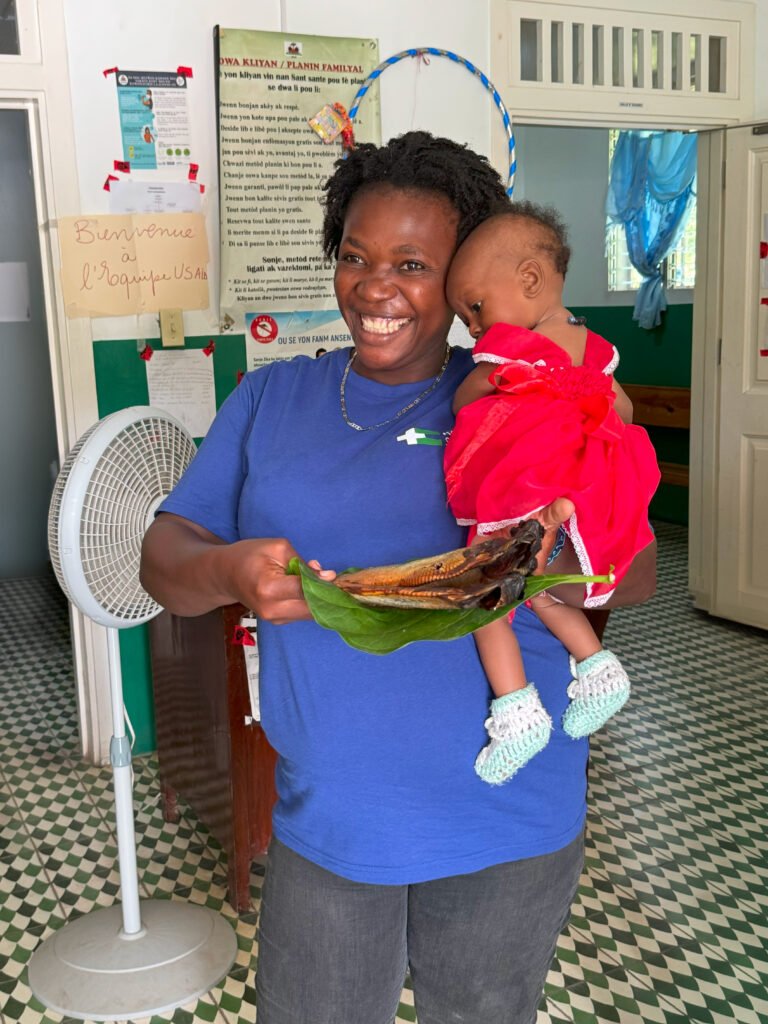 Roseline and her daughter enjoying local dry fish served on a banana leaf after winning a nutrition-focused knowledge contest in southern Haiti in October, 2023.