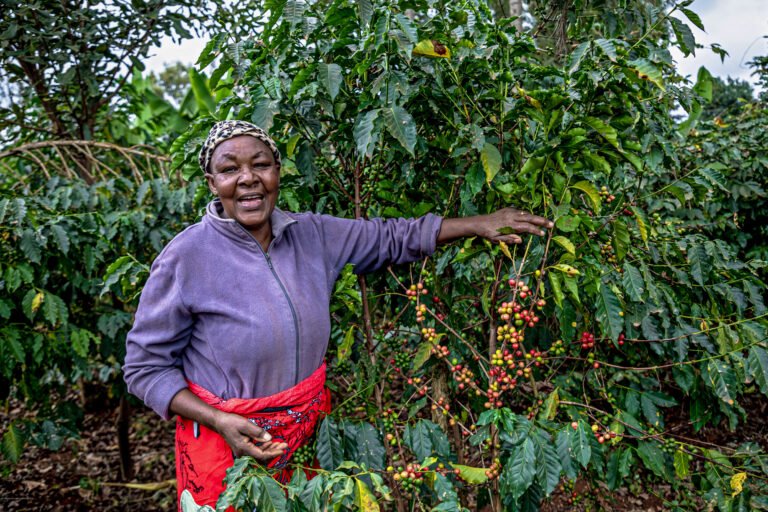 A woman smiles while pointing to her plants.