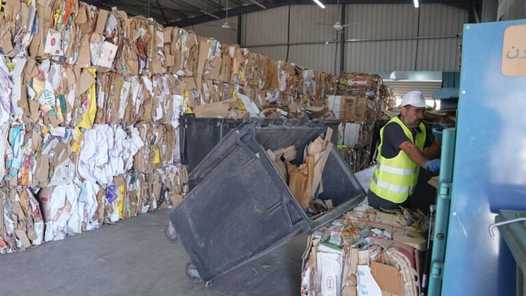 Man in recycling center works with machinery to sort and process recyclables