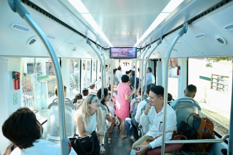 The interior of an electric city bus full of riders.