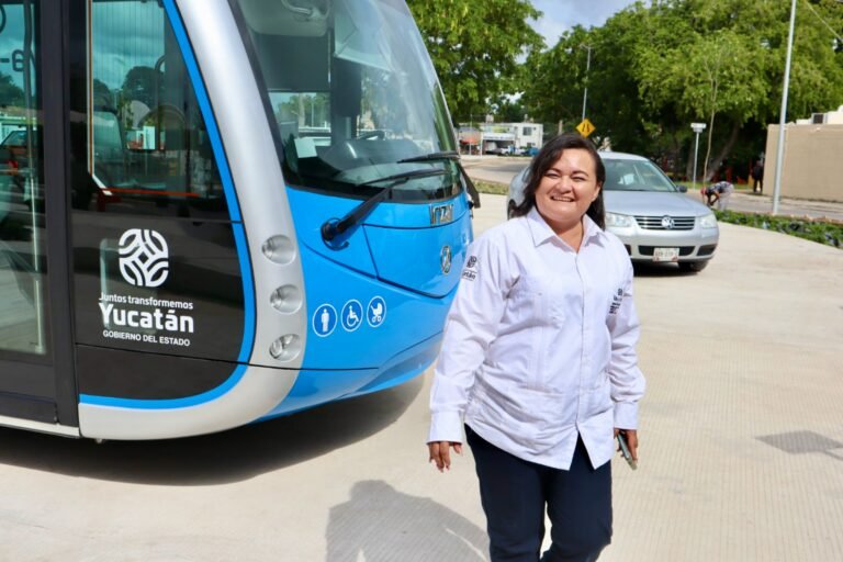 A woman driver smiles while standing in front of an electric bus.