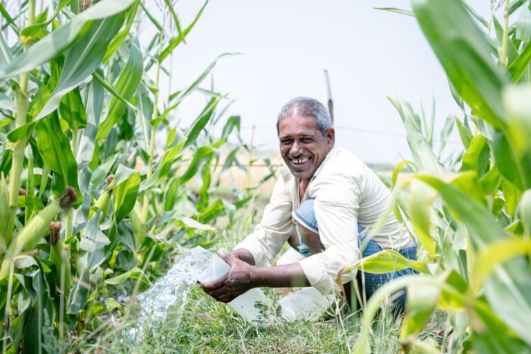 A man smiles while watering his crops.