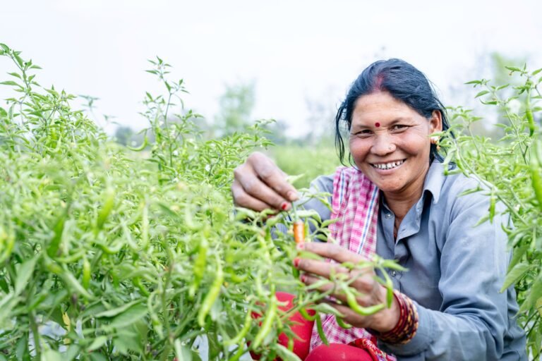 A woman smiles while tending her crops.