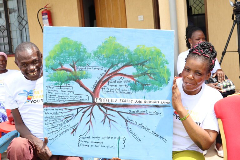 Two community members hold up a poster with a tree diagram outlining the benefits of watershed restoration.