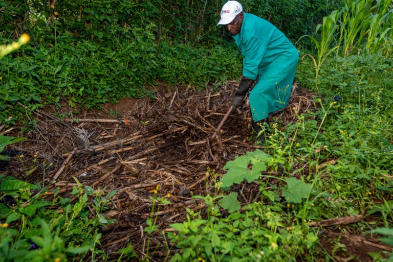 A man mixes compost outside.