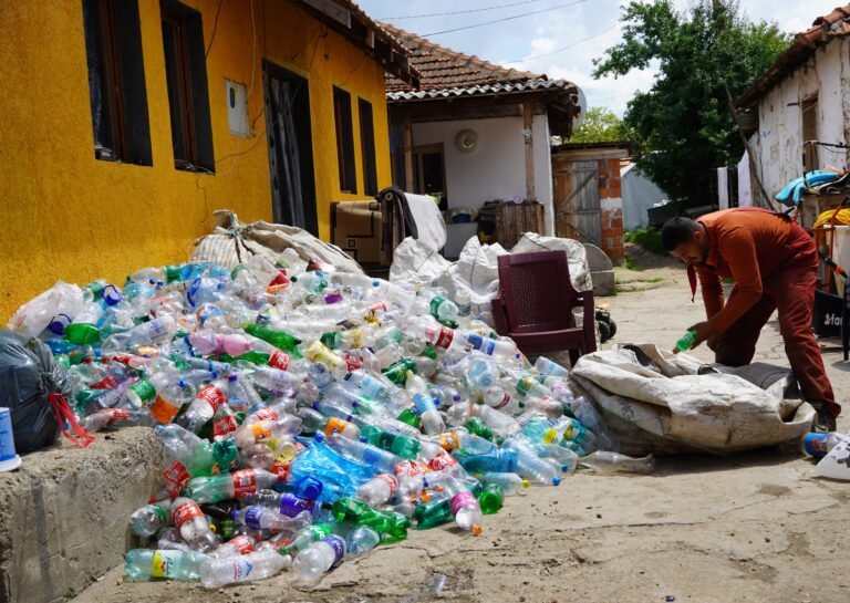 A worker separates recycling in a large pile outside a home.