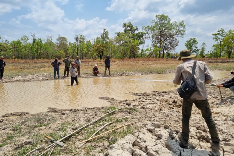 Community members measure one of 16 trapeangs (natural ephemeral pools) that were restored with the support of USAID Morodok Baitang in Cambodia.