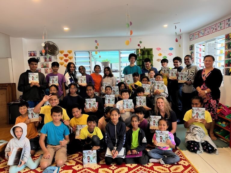 Students of multiple ages hold up books in a classroom.
