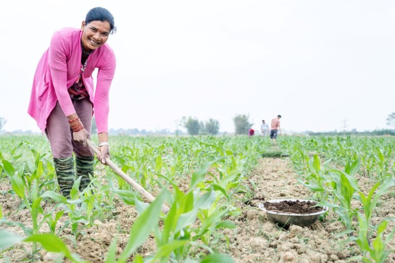 A woman smiles while tending her rows of crops.
