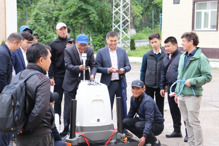 A group of people gather around equipment outside.