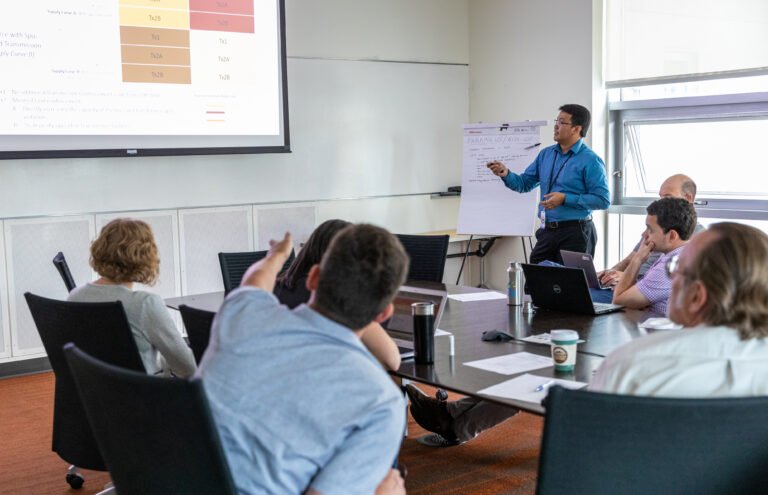 A man presents a PowerPoint slide in front of a group of people.