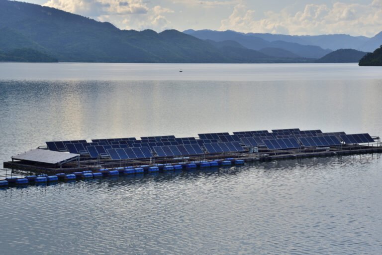 A floating solar plant sits on top of a lake in a mountainous region.