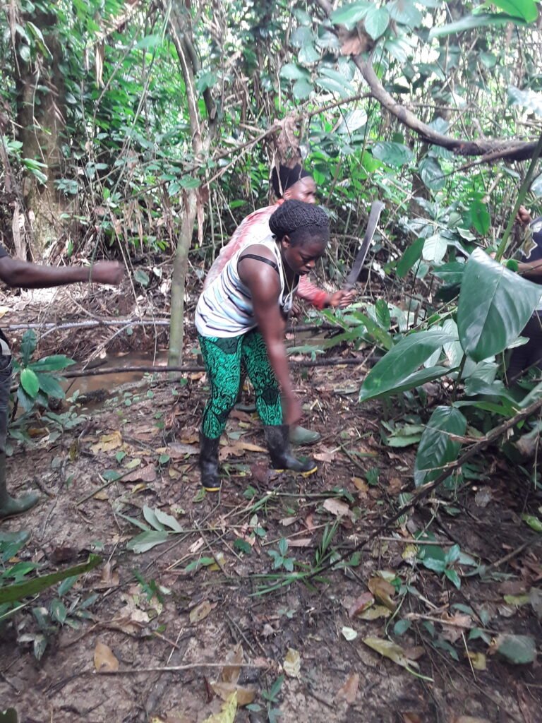 A woman in the forest pointing out a poacher's footprint in the forest.