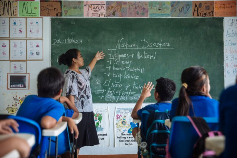 A female teacher leads a class of young students on the topic of natural disasters.