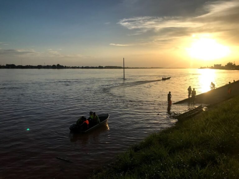 residents play and fish in the rising flood waters in Vientiane, Laos at sunset.