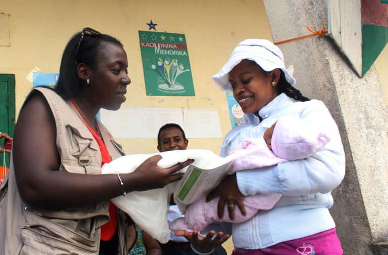 Woman in Madagascar takes a folded mosquito net from a health care worker.