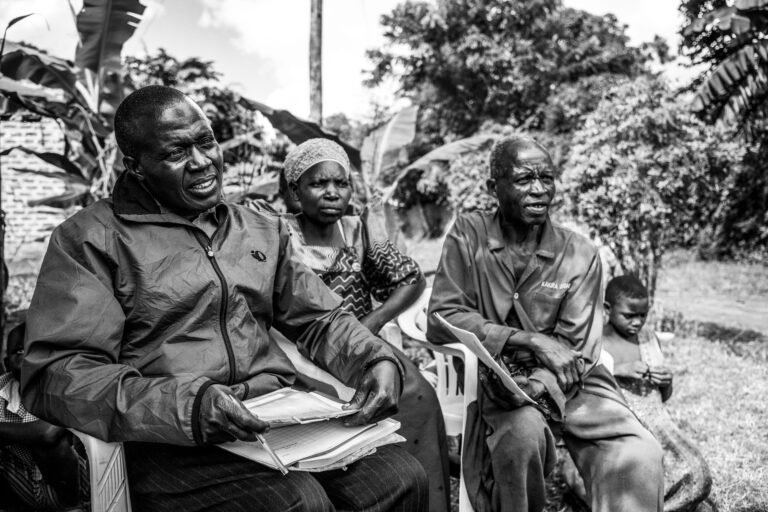 A group of people sit outside, looking toward the camera.