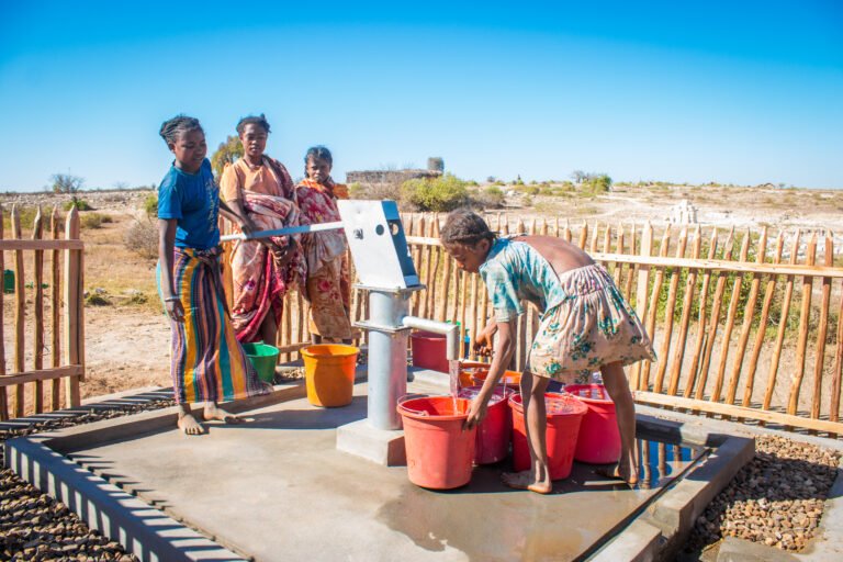 A group of women uses a water point located in an arid area.