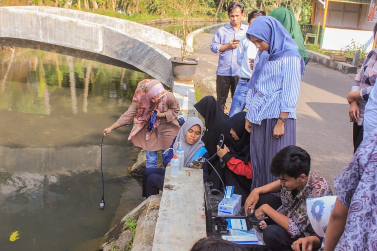 A group of students uses water quality measuring instruments near a river.