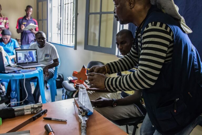 In a classroom, trainees watch a trainer use soil measurement tools.