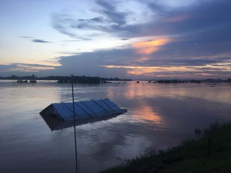 A building submerged in flood waters at dusk.