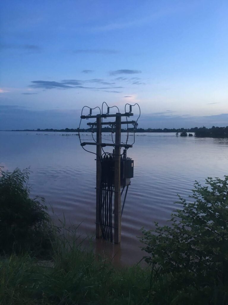 A power distribution line in a flood zone at dusk.